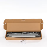 Geöffneter Versandkarton aus brauner Wellpappe, Innen liegen mehrere silberfarbene Aluminiumprofile, Profile sind mit schwarzem Schaumstoff geschützt, Sichtbare Kabel und technische Bauteile im Karton, Vor dem Karton liegen Anleitung und kleines Kabel, Verpackung zeigt den Lieferumfang vor der Montage