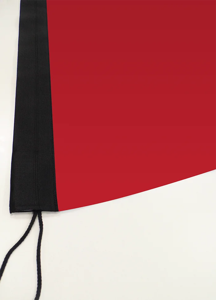 Beachflag Rechteck Large 400 cm: Nahaufnahme der unteren Ecke einer roten Flagge. Sie hat ein breites, schwarzes Besatzband an der linken Seite mit sichtbaren Nähten. Unten hängt eine schwarze Kordel heraus, in Wiesbaden bei City Medien Einkaufswelt für Partner