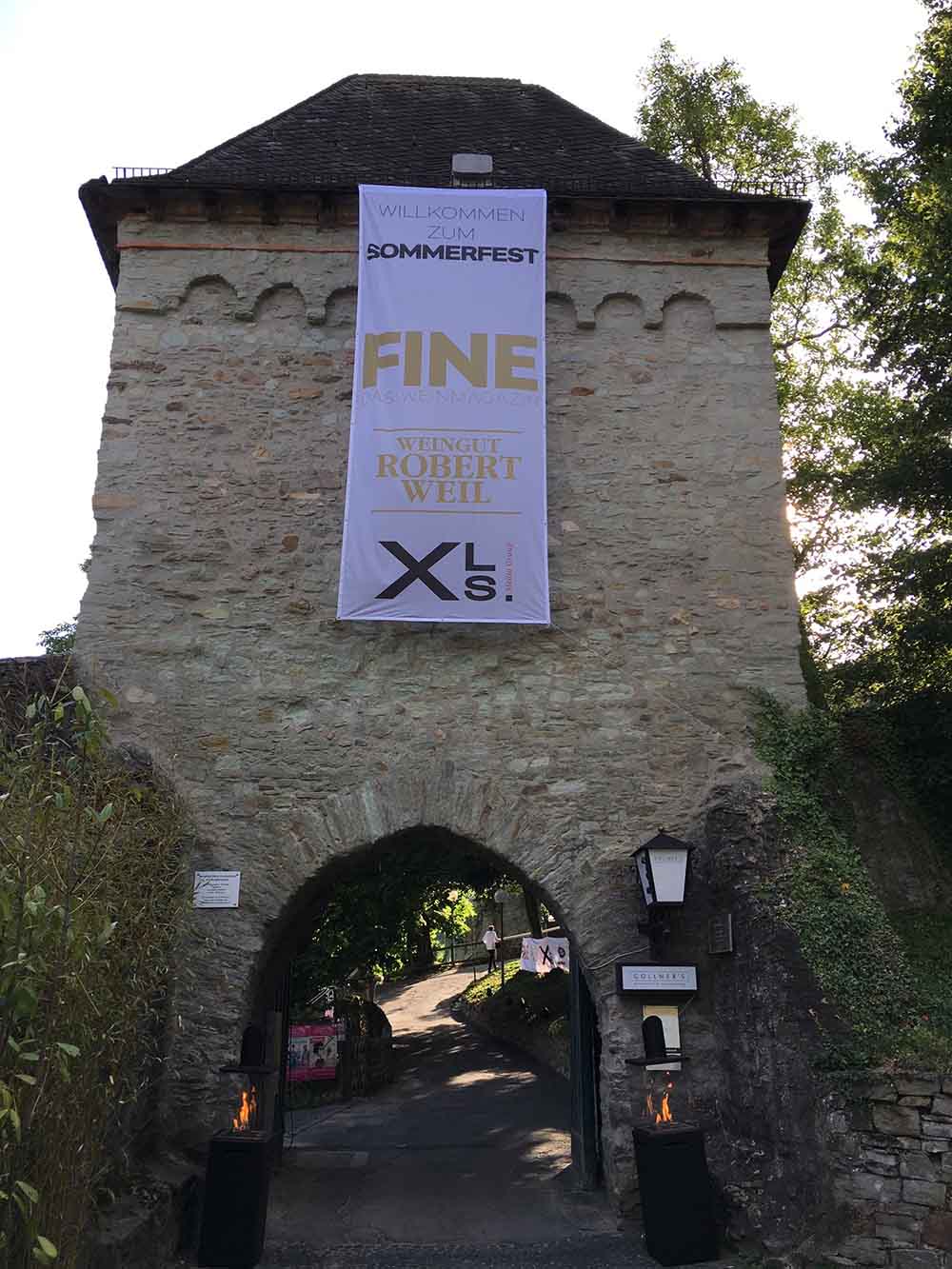 Fahnenstoff Banner – einseitig bedruckt, hochformatiges Textilbanner an historischem Torbogen befestigt, leichter Stoff für Events und Outdoor-Einsatz in Wiesbaden von City Medien Einkaufswelt für Partner günstig kaufen, drucken lassen, online preiswert bestellen – Fahnenstoff Banner, Stoffbanner, Eventwerbung