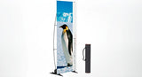 OUTDOOR penguin: Ein aufgestelltes Werbebanner. Das bedruckte Banner zeigt einen Pinguin in einer verschneiten Landschaft. Eine schwarze, zylindrische Transporttasche mit Tragegurt steht daneben, in Wiesbaden bei City Medien Einkaufswelt für Partner
