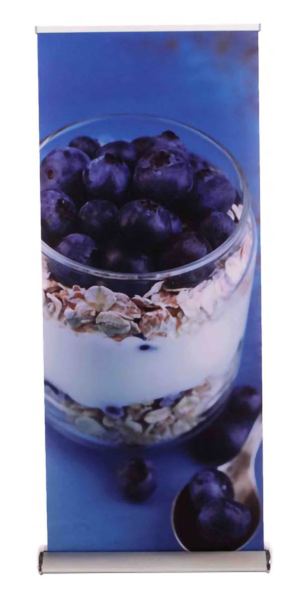 Roll Up Deluxe B 85 cm x H 153-200 cm: Ein hochformatiges Roll-Up-Display mit einem bedruckten Banner. Das Banner zeigt ein Joghurt- oder Müsli-Glas mit Blaubeeren vor einem blauen Hintergrund, in Wiesbaden bei City Medien Einkaufswelt für Partner