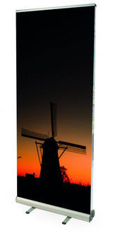 Roll Up Double B 85 cm x H 200 cm: Ein hochformatiges, beidseitig bedrucktes Roll-Up-Display. Das Display zeigt ein Foto einer Windmühle bei Sonnenuntergang und steht auf einer silbernen Kassette mit zwei ausklappbaren Füßen, in Wiesbaden bei City Medien Einkaufswelt für Partner