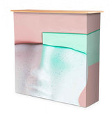 Textilfalttheke B 106 cm x H 102 x T 36 cm: Eine bedruckte Falttheke mit einem abstrakten, dreifarbigen Motiv in Pastellrosa, Mintgrün und Weiß mit grauen Sprenkeln. Die Tischplatte ist aus hellbraunem Holz und der Stoff ist über das Gestell gespannt, in Wiesbaden bei City Medien Einkaufswelt für Partner