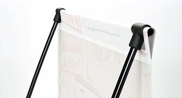 TRAVEL penguin: Nahaufnahme der oberen Befestigung des Banners. Zwei schwarze, gebogene Stangen werden durch einen schwarzen Halter, in dem die bedruckte Bannerkante befestigt ist, zusammengehalten, in Wiesbaden bei City Medien Einkaufswelt für Partner