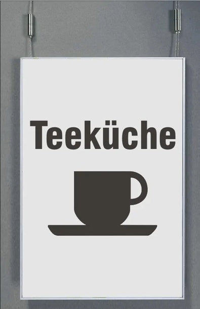 Deckenhänger System Karlsruhe: Ein rechteckiges Schild mit einem silbernen Aluminiumrahmen. Auf dem Schild steht in schwarzer Schrift „Teeküche“ und darunter ist eine schwarze Tasse mit Untertasse abgebildet. Das Schild hängt an zwei silbernen Drahtseilen von der Decke, in Wiesbaden bei City Medien Einkaufswelt für Partner