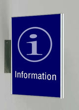 Fahnenschild System Seeshaupt: Ein rechteckiges, blaues Schild mit silbernem Rahmen. Darauf ist in Hellblau ein großes „i“ in einem Kreis und darunter das Wort „Information“ in weißer Schrift. Das Schild ist hochkant an einer silbernen Halterung an der Wand montiert, in Wiesbaden bei City Medien Einkaufswelt für Partner