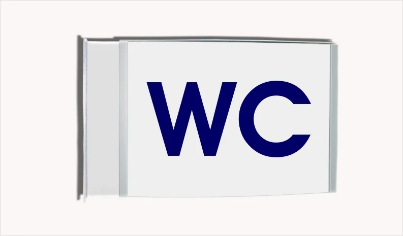 Fahnenschild System Zenit: Ein rechteckiges, weißes Schild mit silbernem Rahmen. Darauf ist in blau das Wort WC geschrieben. Das Schild ist quer an einer silbernen Halterung an der Wand montiert, in Wiesbaden bei City Medien Einkaufswelt für Partner