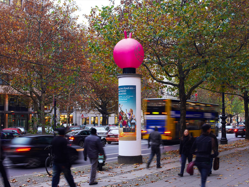 Aufblasbarer Hüpfball auf Werbesäule an baumgesäumter Straße, lebhafter Verkehr – Sonderproduktion Outdoor, City Medien Einkaufswelt für Partner Wiesbaden – Kategorien: Sonderproduktion, Aufblasbare Werbung – anfragen, produzieren lassen, bestellen
