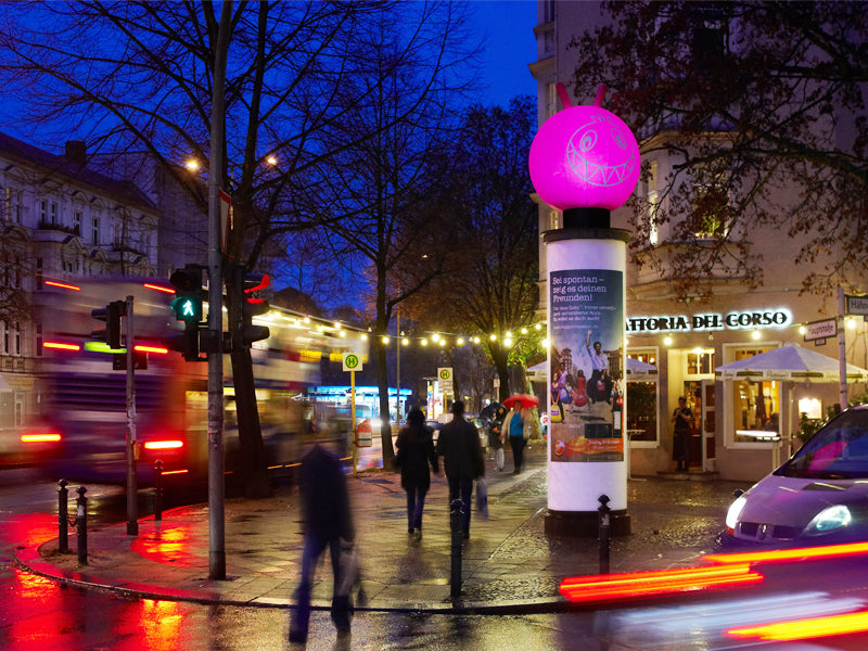 Pinkes Inflatable auf Säule an belebter Kreuzung in der Abenddämmerung – Sonderproduktion für Promotions & Launches, City Medien Einkaufswelt für Partner Wiesbaden – Kategorien: Sonderproduktion, Aufblasbare Werbung – anfragen, produzieren lassen, bestellen
