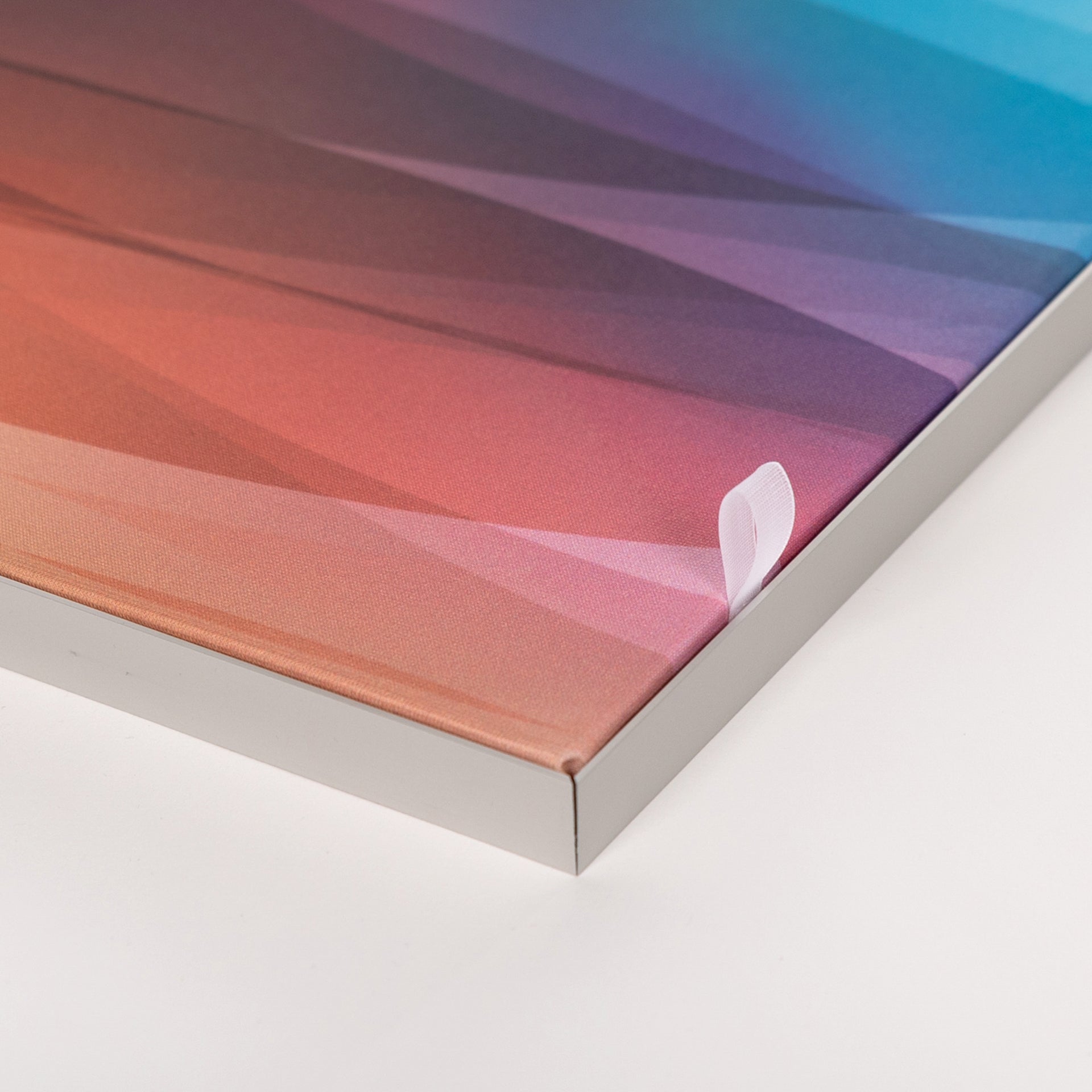 Detailaufnahme einer Ecke des Textil-Spannrahmens, Glatt gespanntes, bedrucktes Textil im Rahmen, Feine Gewebestruktur sichtbar, Silberfarbenes Aluminiumprofil mit sauberer Eckverbindung, Kleine weiße Zuglasche am rechten Rand