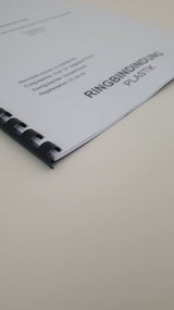 Abschlussarbeit Plastik Spiralbindung 201 bis 400 Seiten: Detailaufnahme des unteren, rechten Teils einer Abschlussarbeit. Das Cover ist weiß, bedruckt und mit einer schwarzen Plastik-Spiralbindung gebunden. Der Text „RINGBINDUNG PLASTIK“ ist am rechten Rand gedruckt, in Wiesbaden bei City Medien Einkaufswelt für Partner