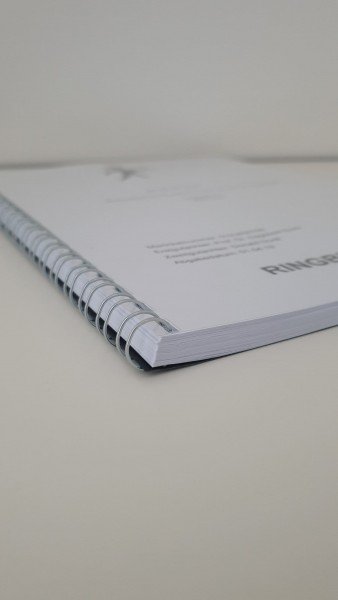 Abschlussarbeit Metall-Spiralbindung: Detailaufnahme des unteren, rechten Teils einer Abschlussarbeit. Das Cover ist weiß, bedruckt und mit einer silbernen Metall-Spiralbindung gebunden. Der Text „RINGBINDUNG METALL“ ist am rechten Rand gedruckt, in Wiesbaden bei City Medien Einkaufswelt für Partner