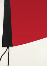 Beachflag Rechteck Austauschdruck: Nahaufnahme der unteren Ecke einer roten Flagge. Sie hat ein breites, schwarzes Besatzband an der linken Seite mit sichtbaren Nähten. Unten hängt eine schwarze Kordel heraus, in Wiesbaden bei City Medien Einkaufswelt für Partner