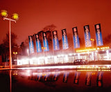 Hissflaggen mit Ausleger: Mehrere blaue Hissflaggen mit weißem 'FSV Frankfurt 1899 e.V.'-Druck stehen im Dunkeln vor einem Gebäude mit der Aufschrift 'Commerzbank-Arena'. Die Flaggen werden von Lichtern angestrahlt und spiegeln sich im Wasser, in Wiesbaden bei City Medien Einkaufswelt für Partner