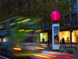 Aufblasbarer Hüpfball-Topper auf Litfaßsäule, vorbeifahrender Bus (Bewegungsunschärfe) – aufmerksamkeitsstarke Außeninszenierung, City Medien Einkaufswelt für Partner Wiesbaden – Kategorien: Sonderproduktion, Aufblasbare Werbung – anfragen, produzieren lassen, bestellen