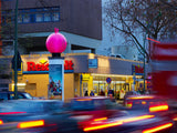 Sonderbau Hüpfball in Magenta auf Reklamesäule, Stadtverkehr bei Dämmerung – 3D-Eyecatcher für Außenwerbung, City Medien Einkaufswelt für Partner Wiesbaden – Kategorien: Sonderproduktion, Aufblasbare Werbung – anfragen, produzieren lassen, bestellen