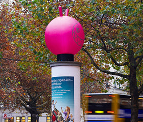 Pinkfarbener aufblasbarer Hüpfball als Sonderproduktion auf Litfaßsäule im Straßenraum – aufmerksamkeitsstarke 3D-Werbung für Outdoor-Kampagnen, City Medien Einkaufswelt für Partner Wiesbaden – Kategorien: Sonderproduktion, Aufblasbare Werbung, 3D-Sonderbau – anfragen, produzieren lassen, bestellen